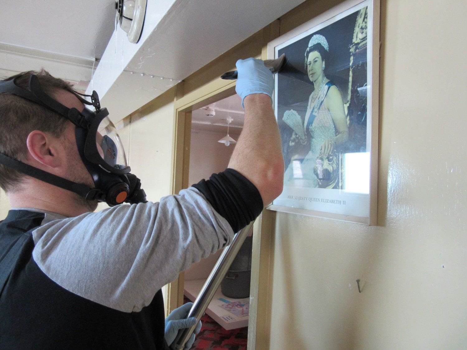 Ciaran cleans a portrait of HM the Queen inside the TAE hut