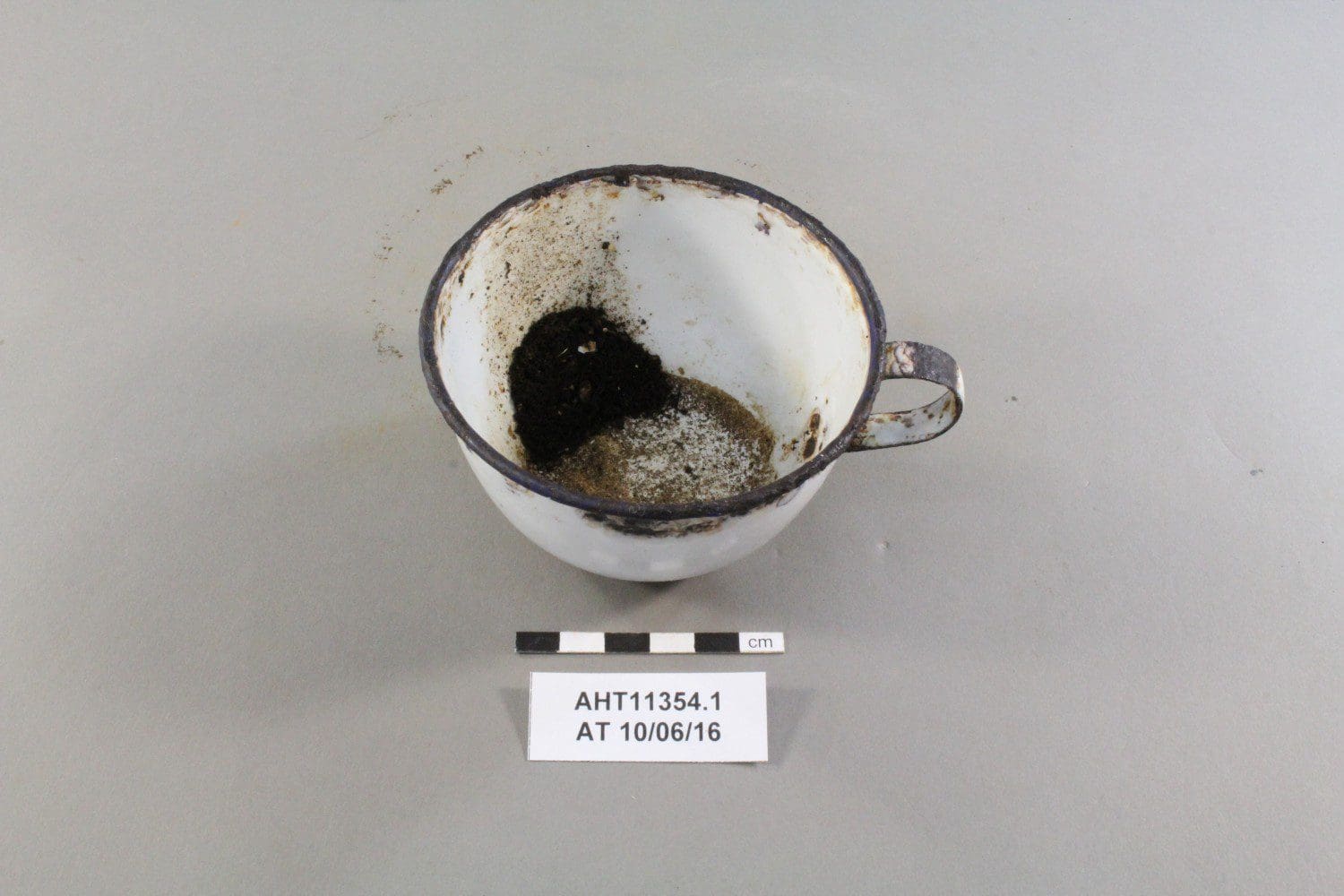 The enamelled mug after conservation with the remains of the last cup of tea still visible in the mug.