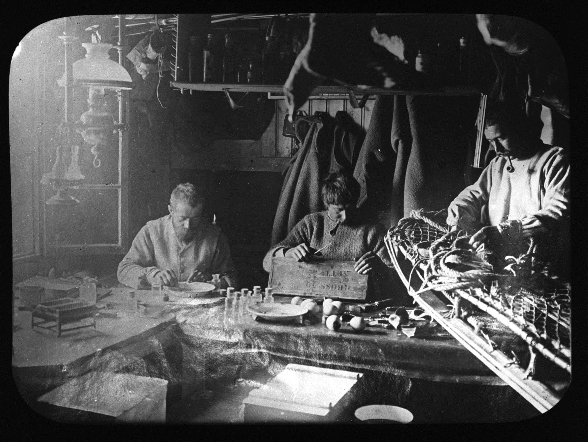 Fougner, Evans and Colbeck working inside the hut in November 1899.