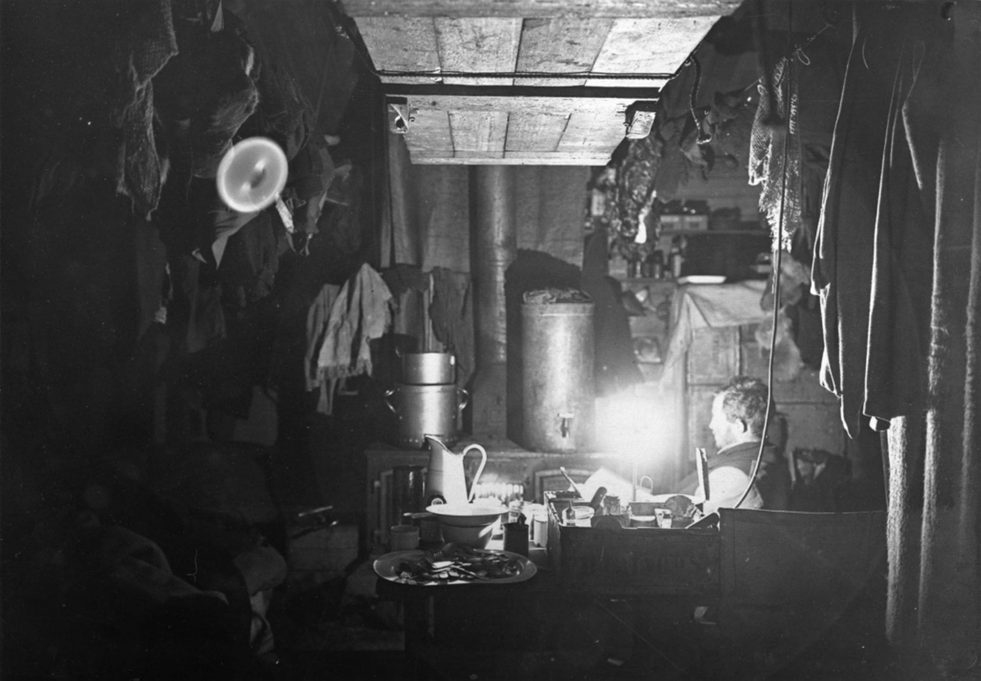 Douglas Mawson (1882-1958) on night watch in Shackleton's hut at Cape Royds, Ross Island, Antarctica, by an unknown photographer