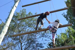Cooperation creating team success on the high ropes course. Erin Didham lends a helping hand to Emily Tipper.