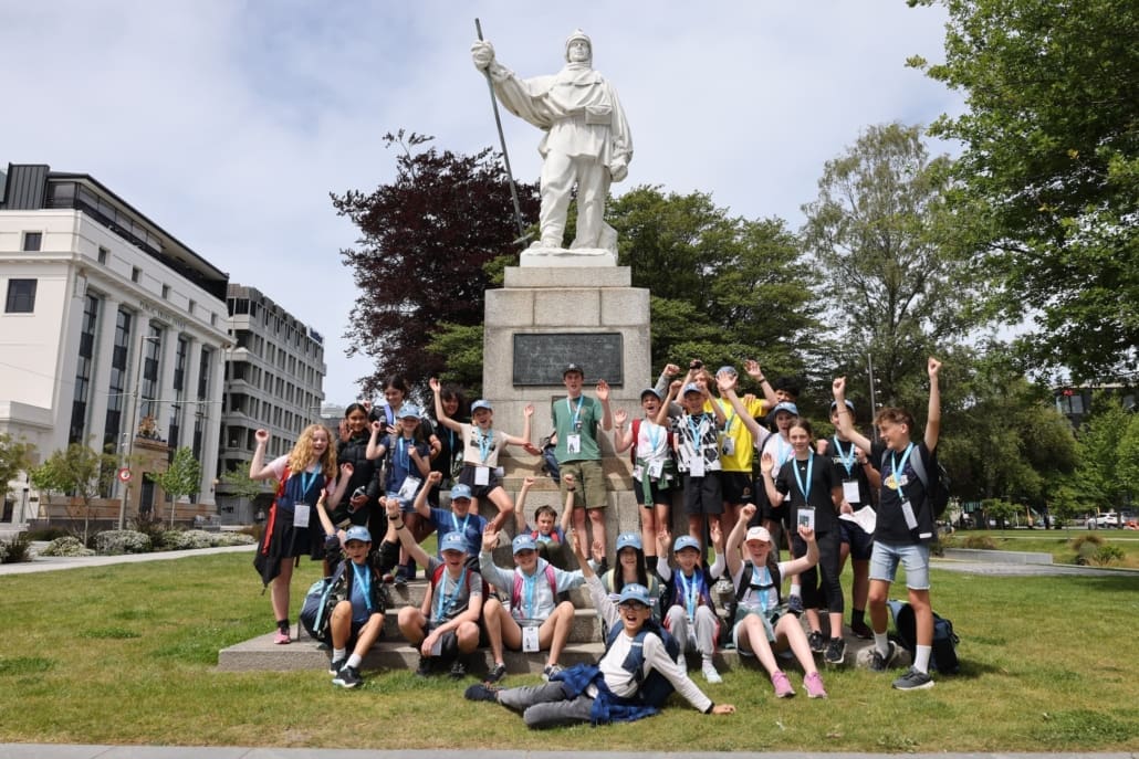 A group of young people standing around a memorial statue of an explorer.