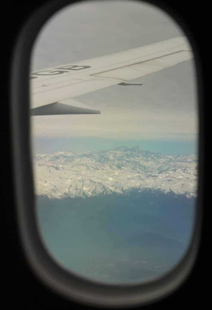 Looking out airplane window to wing and mountains below