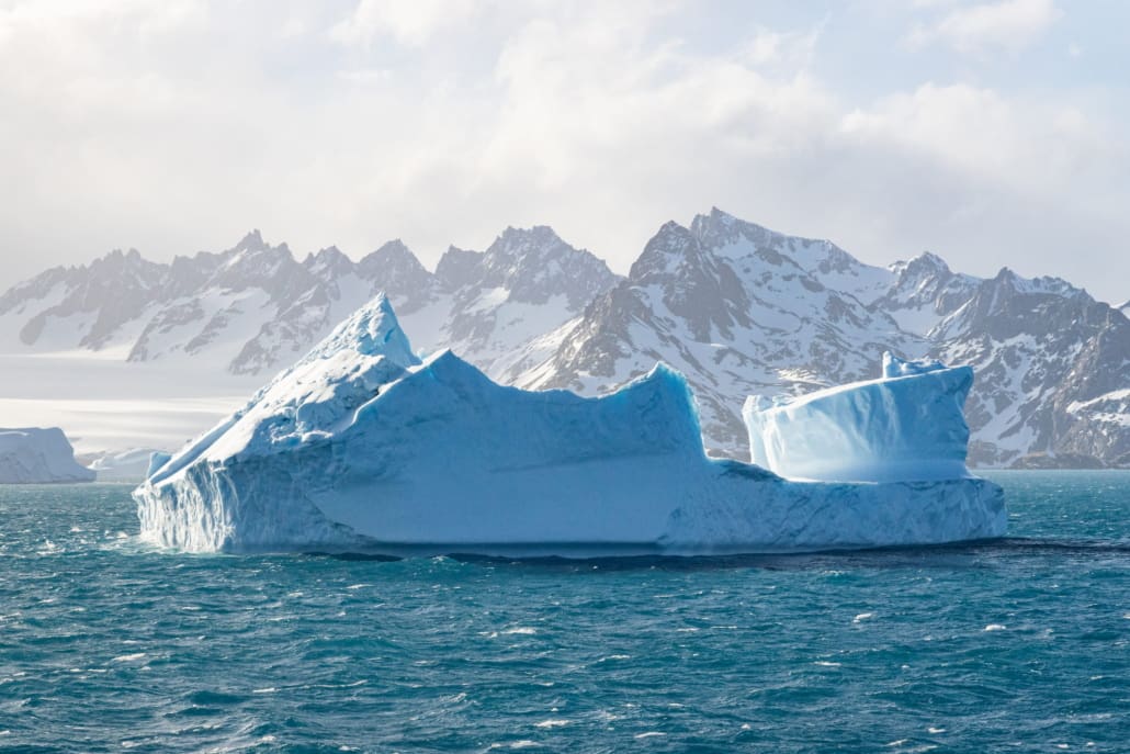 Large ice bergs with snowy mountains in the background.