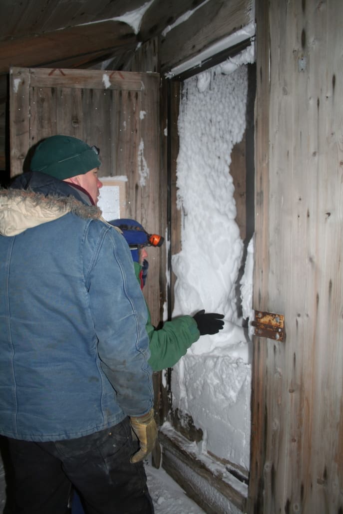 Conservators confronted by a wall of snow and ice filling the entrance to 'Discovery' hut.