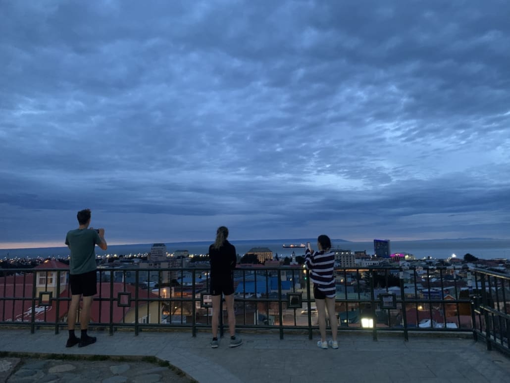 People taking photographs of a sunrise over a city.